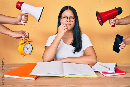 Young beautiful asian girl stuying for university getting stressed out thinking concentrated about doubt with finger on chin and looking up wondering photo