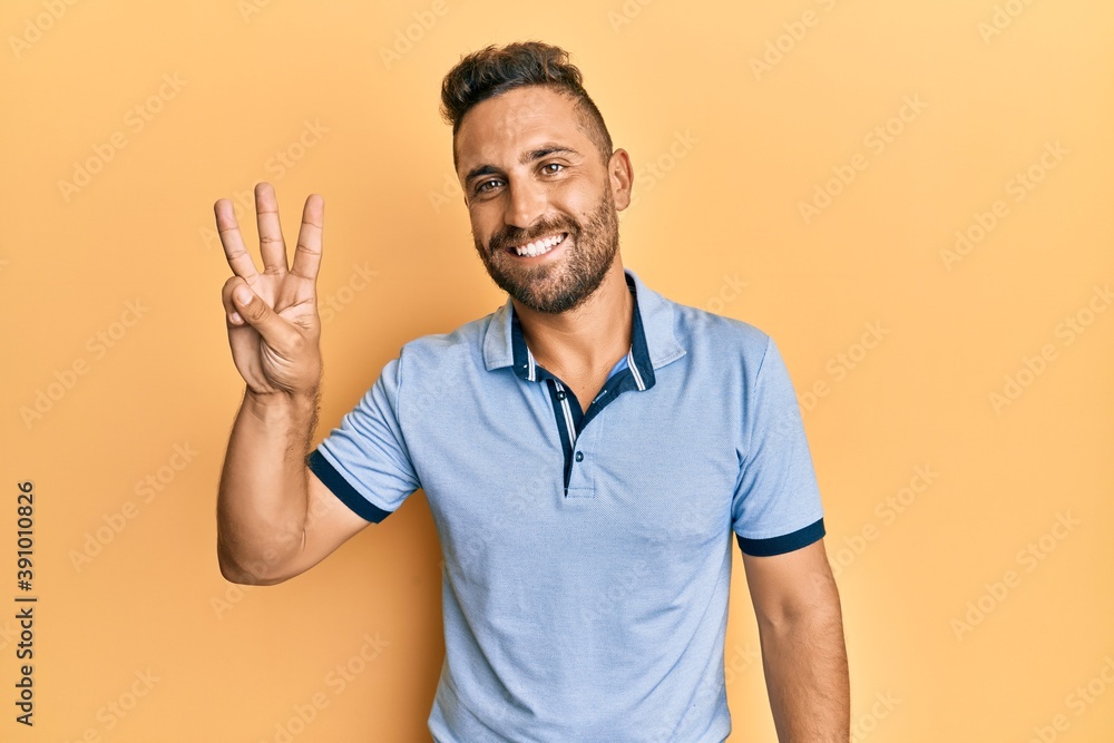 Handsome man with beard wearing casual clothes showing and pointing up with fingers number three while smiling confident and happy. Handsome man with beard wearing casual clothes showing and pointing up with fingers number three while smiling confident and happy.