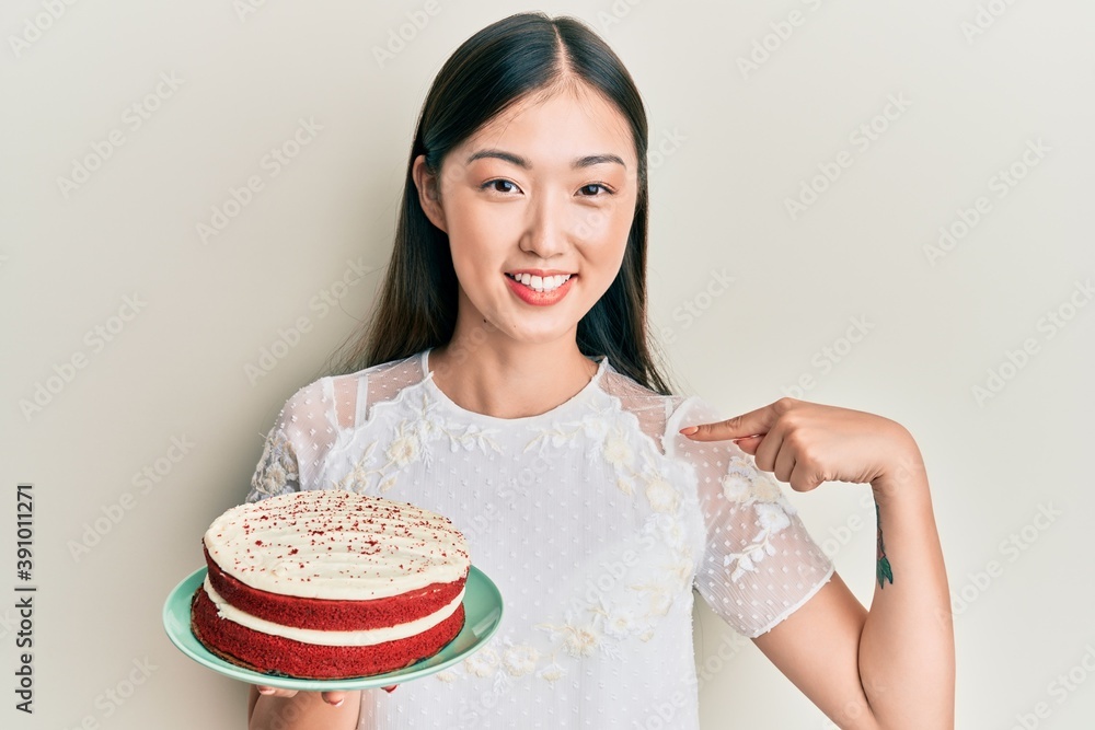 Young chinese woman holding carrot cake pointing finger to one self smiling happy and proud Young chinese woman holding carrot cake pointing finger to one self smiling happy and proud