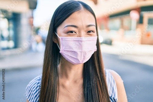 Young chinese woman wearing medical mask walking at street of city.