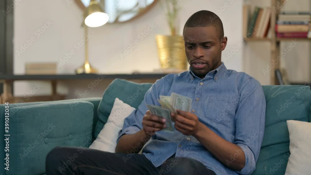 Successful Young African Man Counting Dollar on Sofa Successful Young African Man Counting Dollar on Sofa