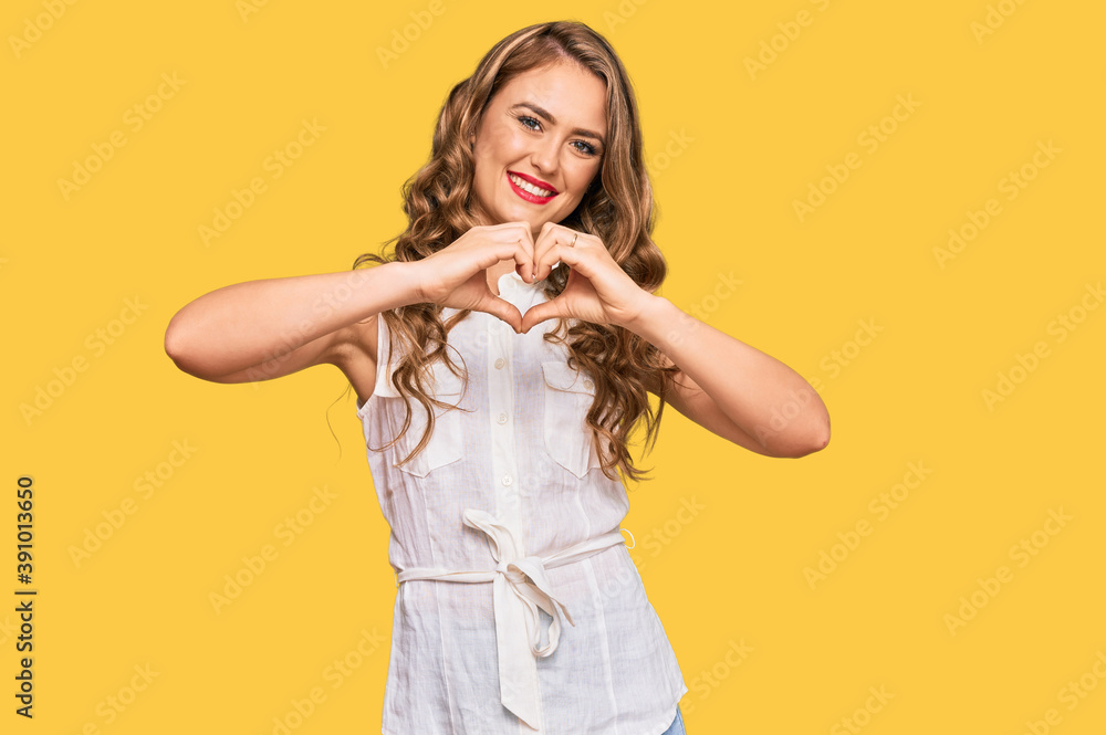Young blonde girl wearing casual clothes smiling in love doing heart symbol shape with hands. romantic concept. Young blonde girl wearing casual clothes smiling in love doing heart symbol shape with hands. romantic concept.