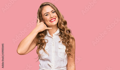 Young blonde girl wearing casual clothes smiling doing phone gesture with hand and fingers like talking on the telephone. communicating concepts.