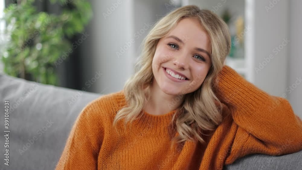 Happy young blonde in yellow sweater smiling while sitting on sofa. Lazy weekends at home Happy young blonde in yellow sweater smiling while sitting on sofa. Lazy weekends at home