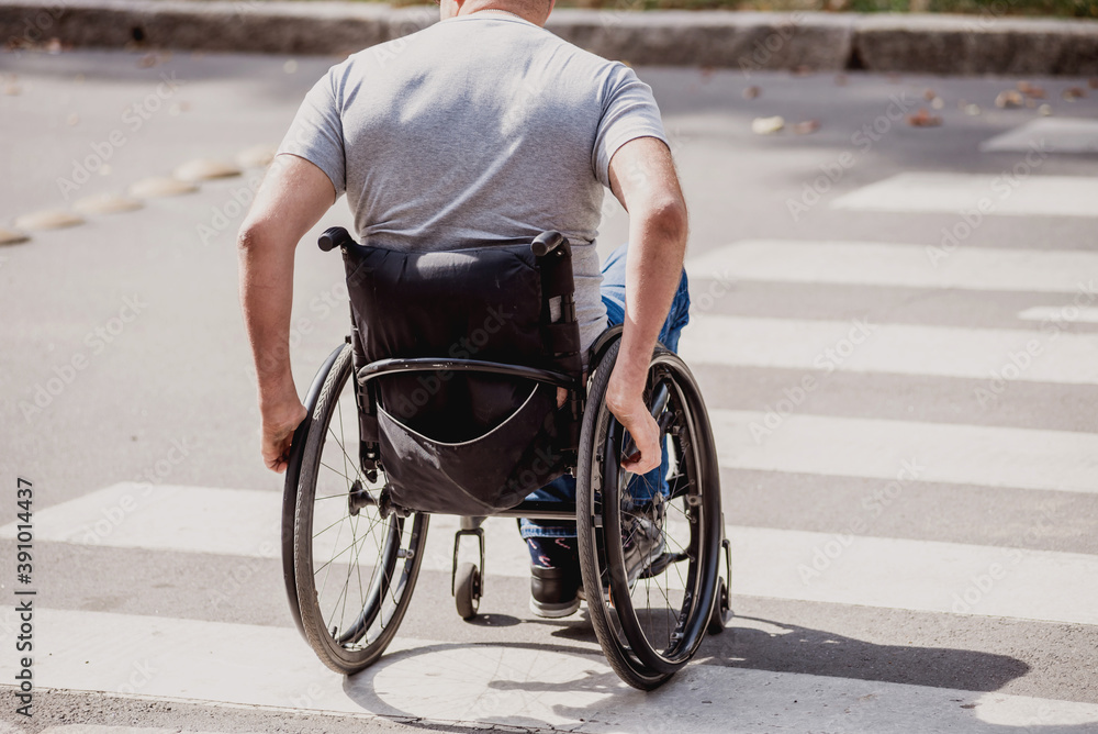 Handicapped man in wheelchair crossing street road Handicapped man in wheelchair crossing street road