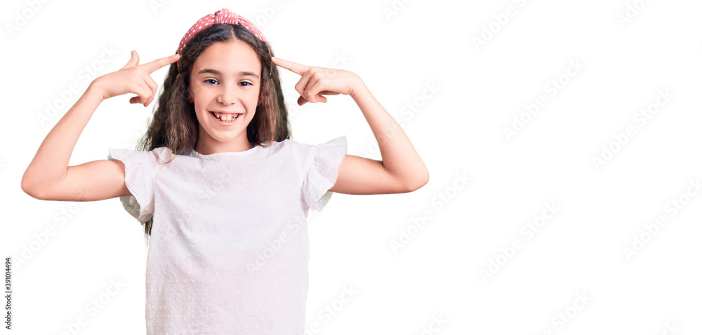 Cute hispanic child girl wearing casual white tshirt smiling pointing to head with both hands finger, great idea or thought, good memory Cute hispanic child girl wearing casual white tshirt smiling pointing to head with both hands finger, great idea or thought, good memory