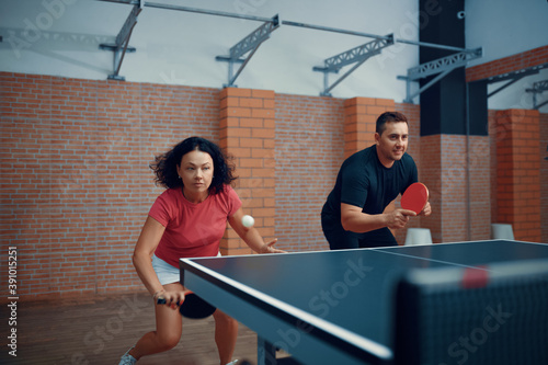 Man and woman play doubles table tennis, ping pong