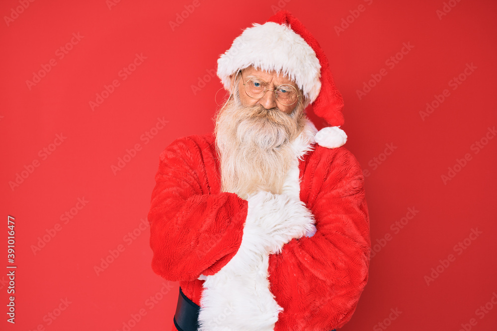Old senior man with grey hair and long beard wearing traditional santa claus costume skeptic and nervous, disapproving expression on face with crossed arms. negative person.