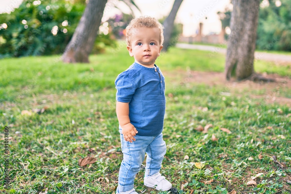 Cute and happy little boy having fun at the park on a sunny day. Beautiful blonde hair male toddler playing outdoors Cute and happy little boy having fun at the park on a sunny day. Beautiful blonde hair male toddler playing outdoors
