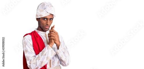 African handsome man wearing tradition sherwani saree clothes holding symbolic gun with hand gesture  playing killing shooting weapons  angry face