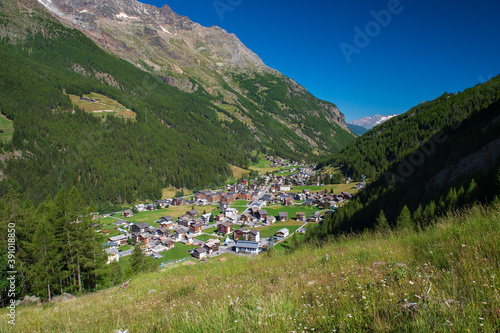 Alpine resort village Saas-Grund lies in Saas valley at 1559m east of Lenzspitze and Dom. Surrounded by snow-covered mountains, green meadows and forests it is a popular travel destination in summer photo