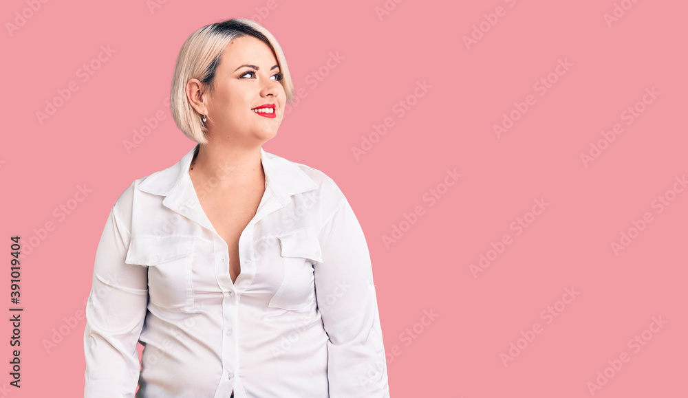 Young blonde plus size woman wearing casual shirt looking away to side with smile on face, natural expression. laughing confident. Young blonde plus size woman wearing casual shirt looking away to side with smile on face, natural expression. laughing confident.