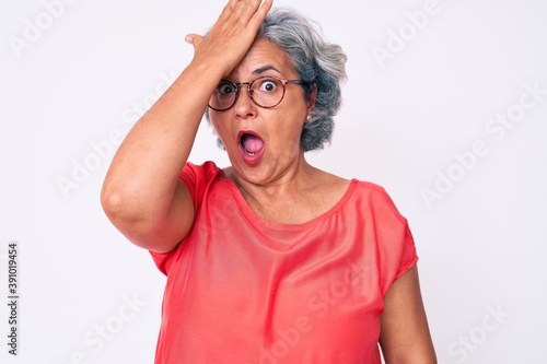 Senior hispanic grey- haired woman wearing casual clothes and glasses surprised with hand on head for mistake, remember error. forgot, bad memory concept.