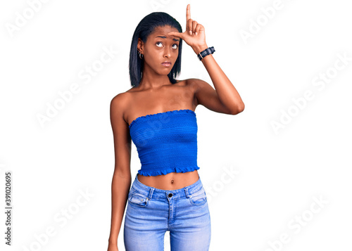 Young african american woman wearing casual summer clothes making fun of people with fingers on forehead doing loser gesture mocking and insulting. photo