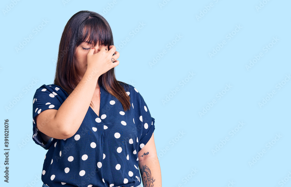 Young plus size woman wearing casual clothes tired rubbing nose and eyes feeling fatigue and headache. stress and frustration concept. Young plus size woman wearing casual clothes tired rubbing nose and eyes feeling fatigue and headache. stress and frustration concept.