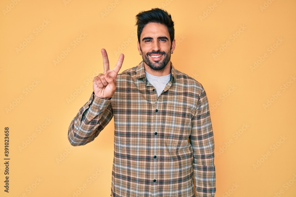 Handsome hispanic man with beard wearing casual clothes showing and pointing up with fingers number two while smiling confident and happy. Handsome hispanic man with beard wearing casual clothes showing and pointing up with fingers number two while smiling confident and happy.