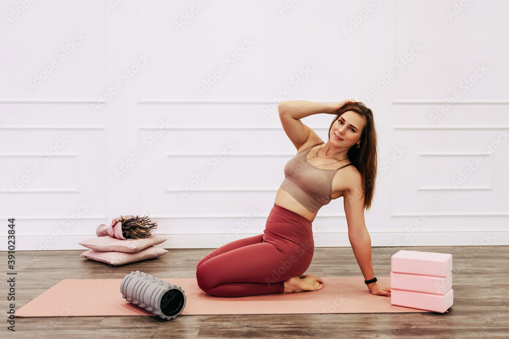 Adult sporty woman doing fascia exercise on the floor. Caucasian female using foam massage roller - tool for back tension and muscle pain release. training stretch concept Adult sporty woman doing fascia exercise on the floor. Caucasian female using foam massage roller - tool for back tension and muscle pain release. training stretch concept