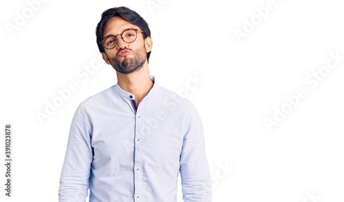 Handsome hispanic man wearing business shirt and glasses looking at the camera blowing a kiss on air being lovely and sexy. love expression. © Krakenimages.com