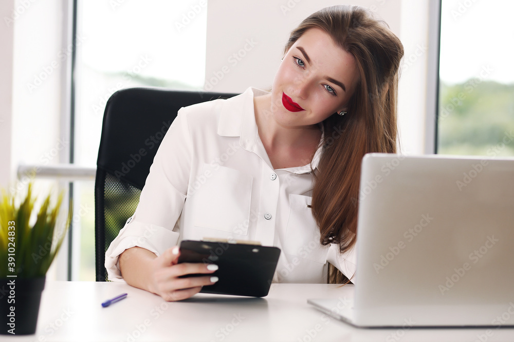 Business woman sitting at a desk with a laptop and looking away in the office Business woman sitting at a desk with a laptop and looking away in the office