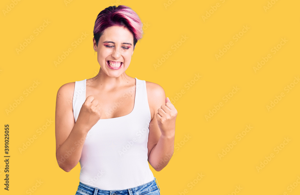 Young beautiful woman with pink hair wearing casual clothes excited for success with arms raised and eyes closed celebrating victory smiling. winner concept. Young beautiful woman with pink hair wearing casual clothes excited for success with arms raised and eyes closed celebrating victory smiling. winner concept.