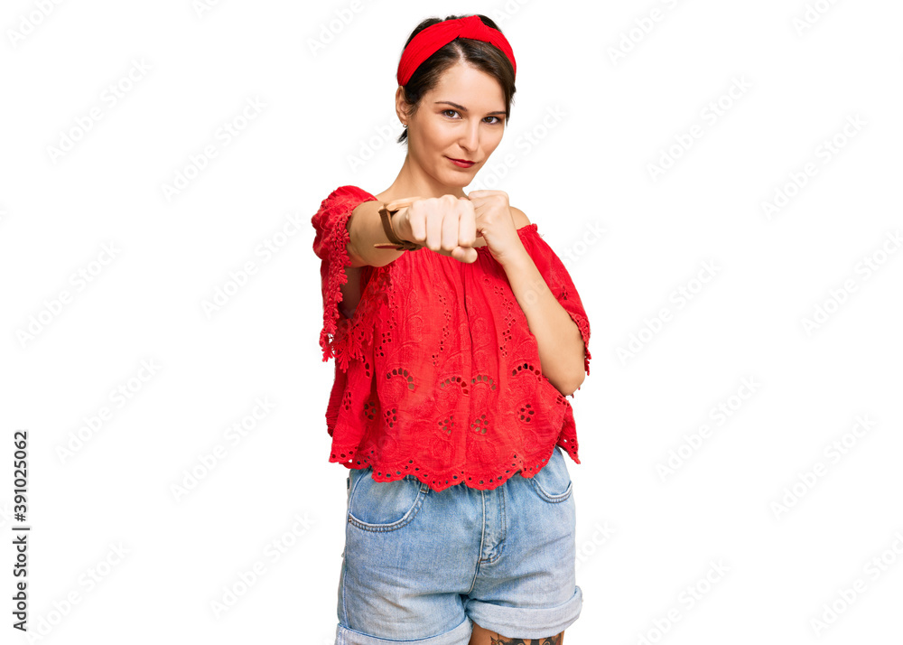 Young brunette woman with short hair wearing casual summer clothes and diadem punching fist to fight, aggressive and angry attack, threat and violence Young brunette woman with short hair wearing casual summer clothes and diadem punching fist to fight, aggressive and angry attack, threat and violence