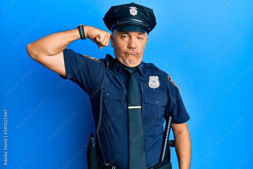 Handsome middle age mature man wearing police uniform strong person showing arm muscle, confident and proud of power Handsome middle age mature man wearing police uniform strong person showing arm muscle, confident and proud of power