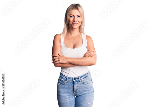 Young beautiful blonde woman wearing casual sleeveless t-shirt happy face smiling with crossed arms looking at the camera. positive person. © Krakenimages.com