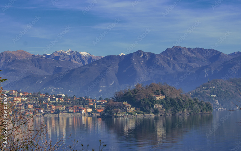 Spectacular panoramic mountain backdrop on a clear day on the lake, with an island and a picturesque village in the foreground.Como Lake,Lombardy,Italian Lakes,Italy