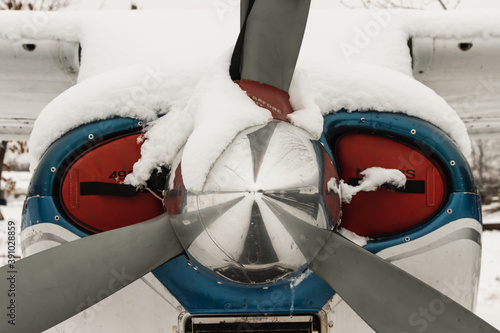 Gray blade, the hood of a small private plane covered with snow, winter in bad weather at the airport.