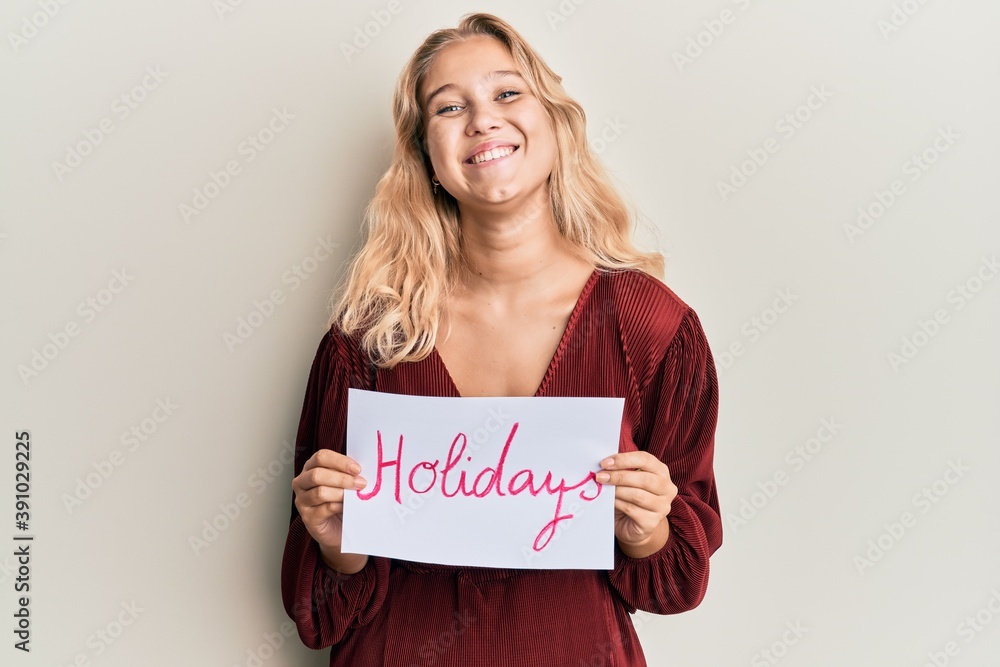 Young blonde girl holding holidays banner message smiling with a happy and cool smile on face. showing teeth. Young blonde girl holding holidays banner message smiling with a happy and cool smile on face. showing teeth.