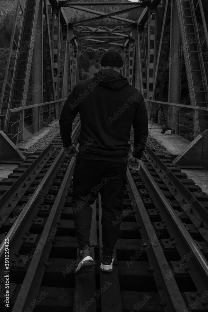 A man walks across a railway bridge