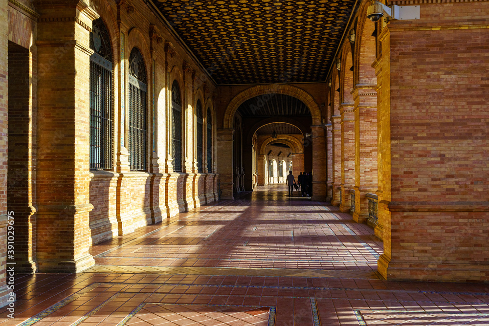 Interior Plaza de España en Sevilla al atardecer en un día soleado, galería que recorre el monumento público.