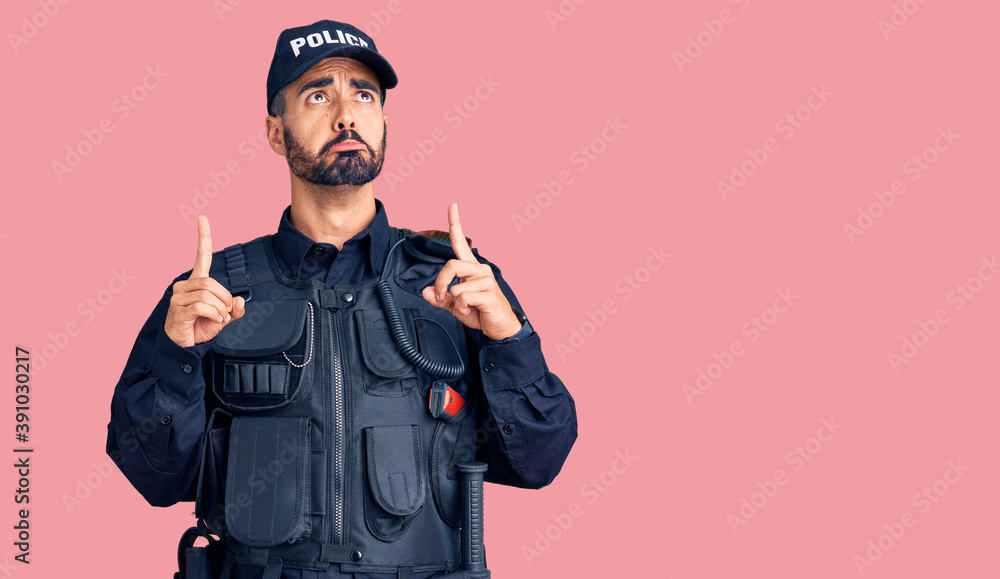 Young hispanic man wearing police uniform pointing up looking sad and upset, indicating direction with fingers, unhappy and depressed. Young hispanic man wearing police uniform pointing up looking sad and upset, indicating direction with fingers, unhappy and depressed.