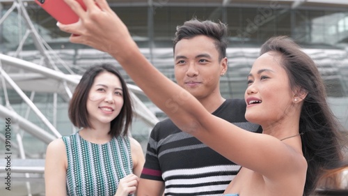 Three asian friends strolling in the city taking selfies. Happiness and tourism concept