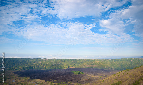 Panorama of popular trek destination Mount Batur eastern ridge at sunrise, with black solidified lava flow field, near Batur, Bali, Indonesia