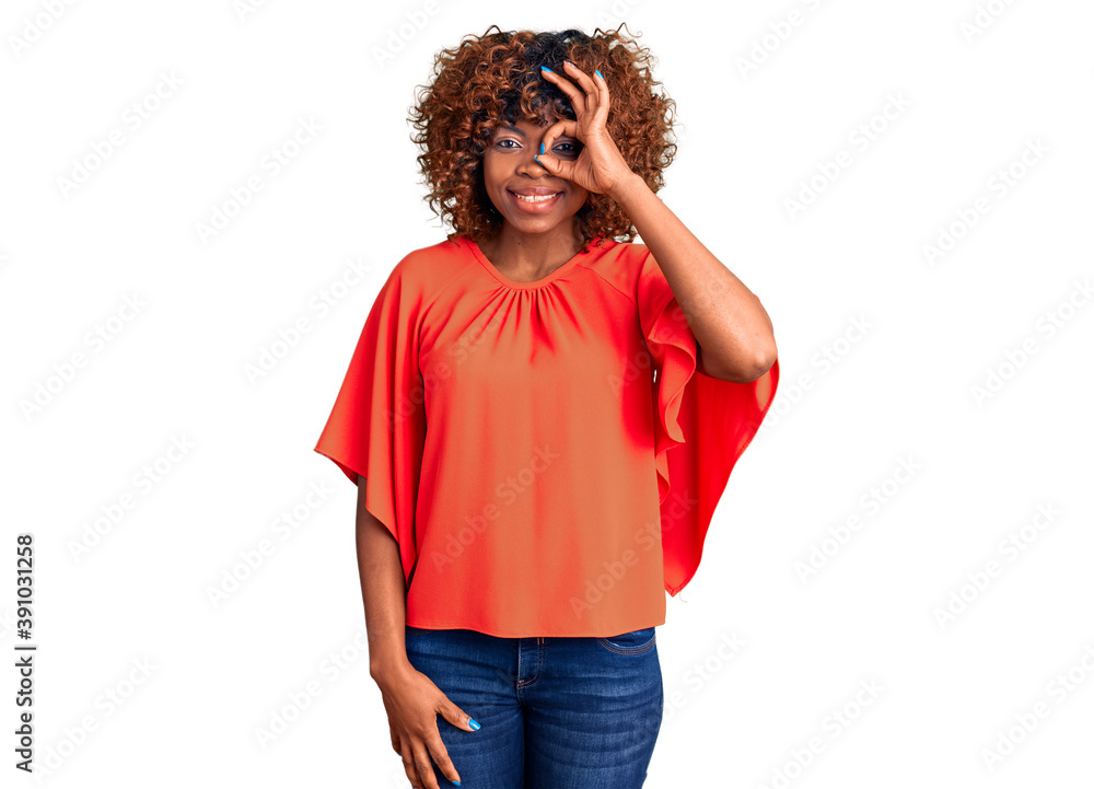 Young african american woman wearing casual clothes doing ok gesture with hand smiling, eye looking through fingers with happy face. Young african american woman wearing casual clothes doing ok gesture with hand smiling, eye looking through fingers with happy face.