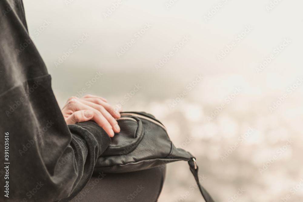 Primo piano di una donna che viaggia in possesso di una borsa in pelle si trova sul bordo di una scogliera tra le montagne.