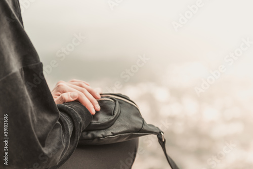 Primo piano di una donna che viaggia in possesso di una borsa in pelle si trova sul bordo di una scogliera tra le montagne. photo