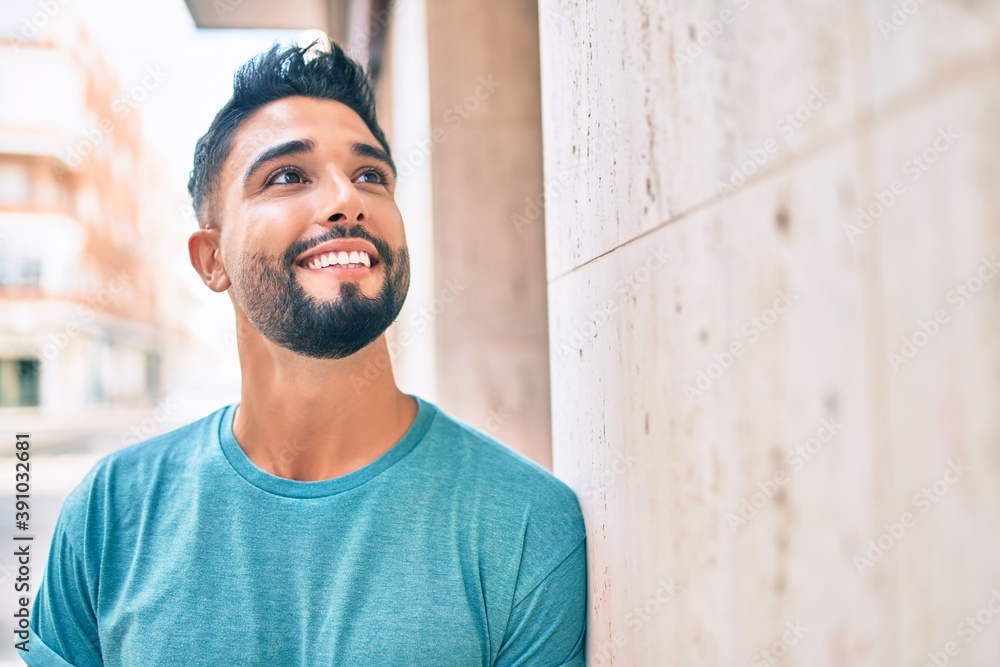 Obraz premium Young arab man smiling happy leaning on the wall at the city.