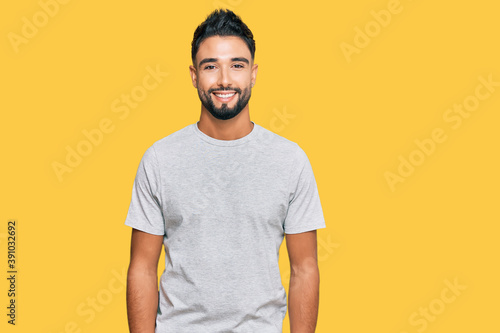 Young man with beard wearing casual grey tshirt with a happy and cool smile on face. lucky person. © Krakenimages.com