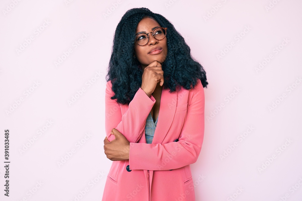 Beautiful african woman wearing business jacket and glasses with hand on chin thinking about question, pensive expression. smiling with thoughtful face. doubt concept. Beautiful african woman wearing business jacket and glasses with hand on chin thinking about question, pensive expression. smiling with thoughtful face. doubt concept.