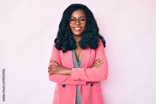 Beautiful african woman wearing business jacket and glasses happy face smiling with crossed arms looking at the camera. positive person. © Krakenimages.com