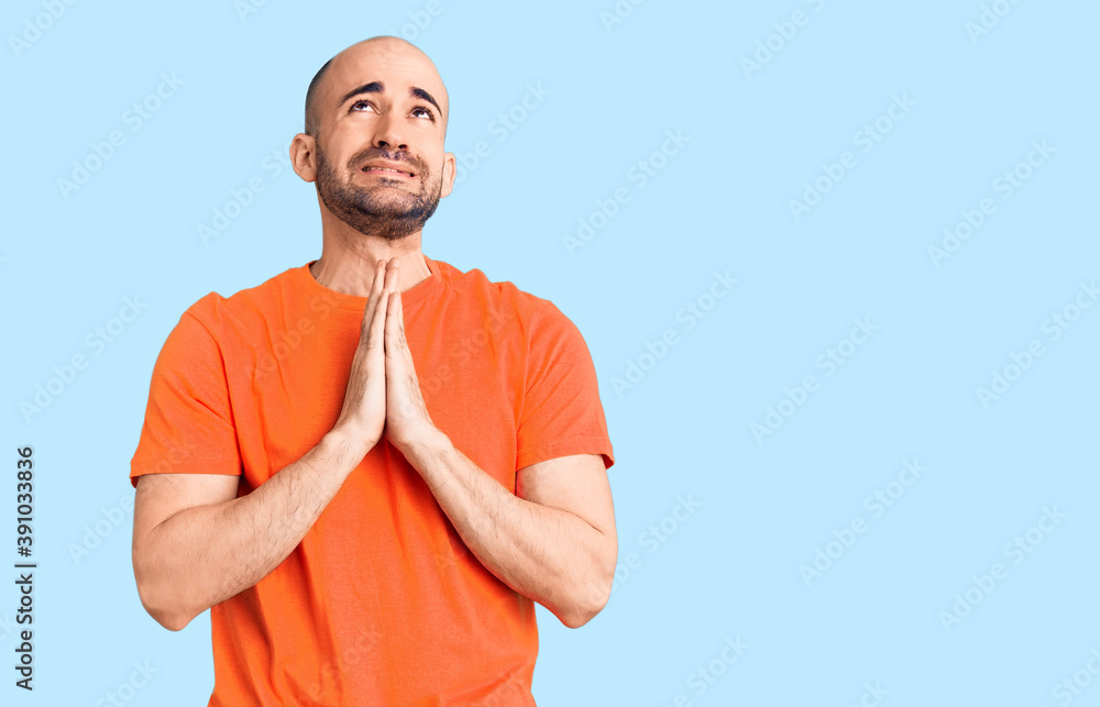 Young handsome man wering casual t shirt begging and praying with hands together with hope expression on face very emotional and worried. begging. Young handsome man wering casual t shirt begging and praying with hands together with hope expression on face very emotional and worried. begging.