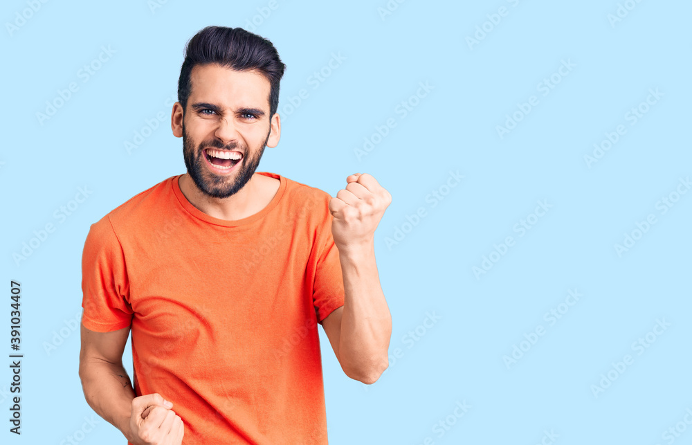 Young handsome man with beard wearing casual t-shirt celebrating surprised and amazed for success with arms raised and eyes closed. winner concept. Young handsome man with beard wearing casual t-shirt celebrating surprised and amazed for success with arms raised and eyes closed. winner concept.