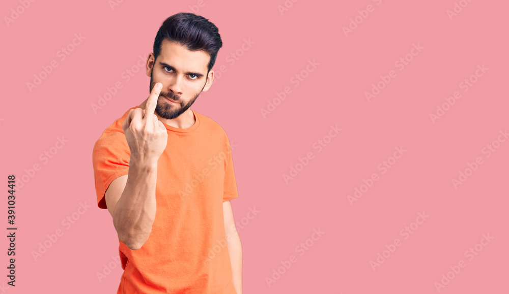 Young handsome man with beard wearing casual t-shirt showing middle finger, impolite and rude fuck off expression Young handsome man with beard wearing casual t-shirt showing middle finger, impolite and rude fuck off expression