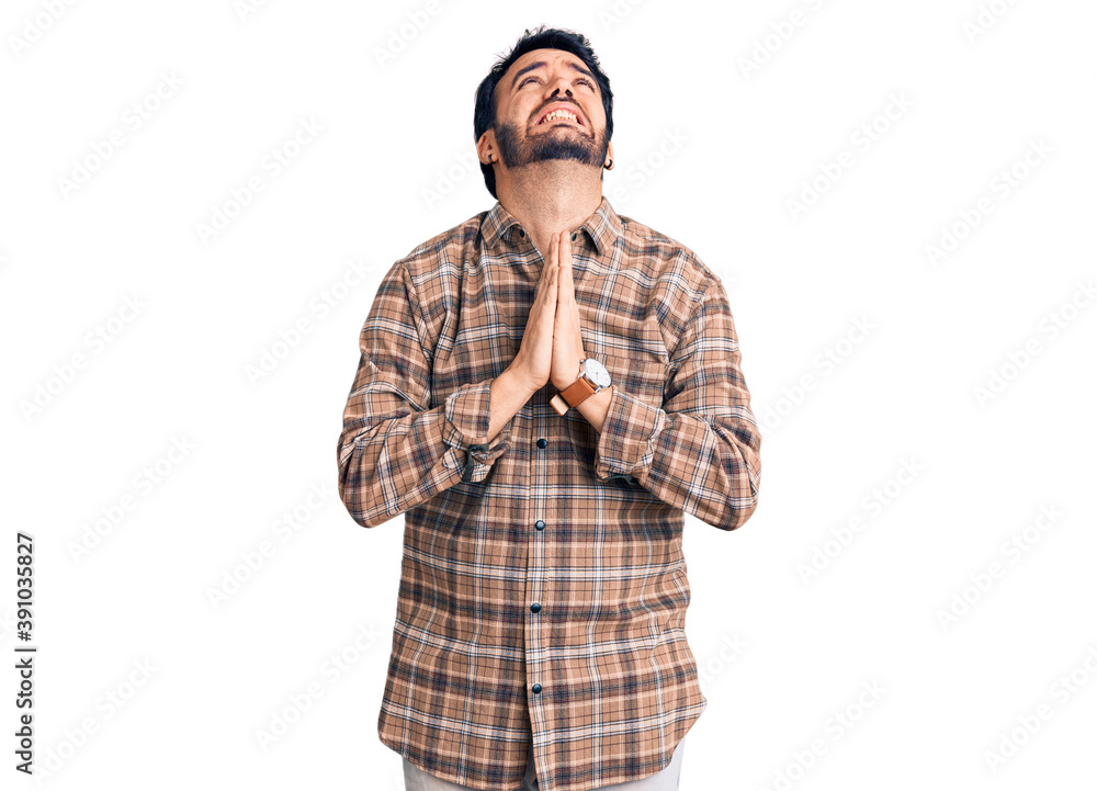 Young hispanic man wearing casual clothes begging and praying with hands together with hope expression on face very emotional and worried. begging. Young hispanic man wearing casual clothes begging and praying with hands together with hope expression on face very emotional and worried. begging.