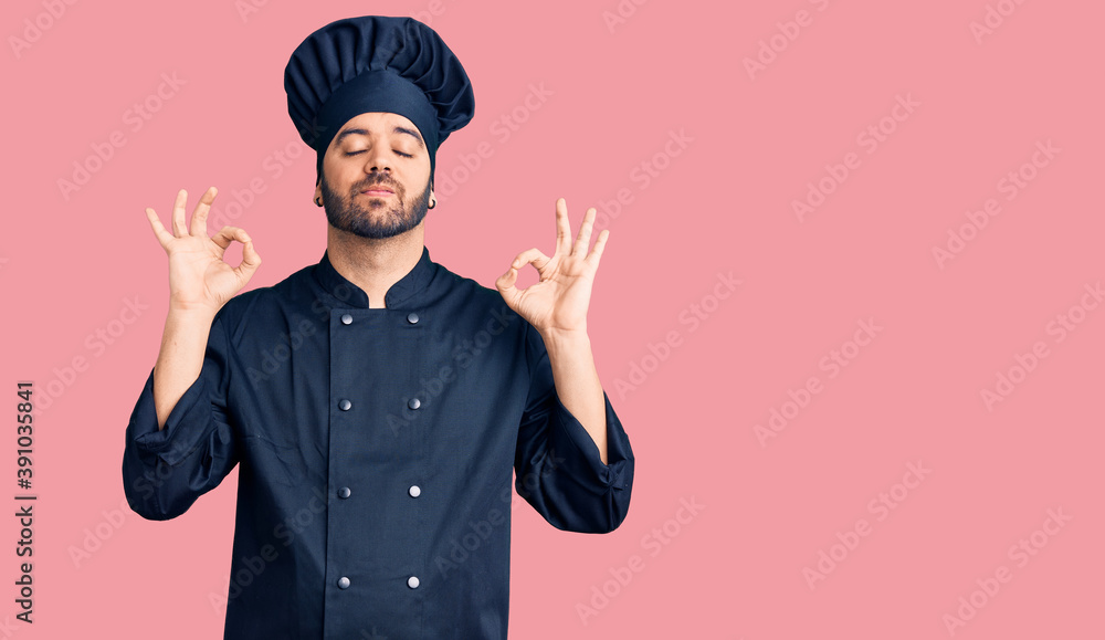 Young hispanic man wearing cooker uniform relax and smiling with eyes closed doing meditation gesture with fingers. yoga concept. Young hispanic man wearing cooker uniform relax and smiling with eyes closed doing meditation gesture with fingers. yoga concept.