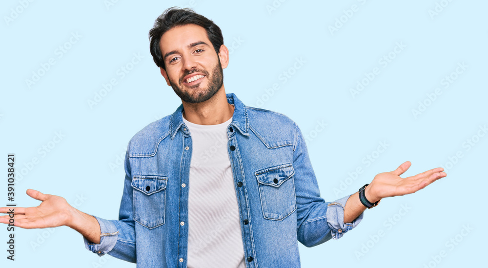 Young hispanic man wearing casual clothes smiling showing both hands open palms, presenting and advertising comparison and balance Young hispanic man wearing casual clothes smiling showing both hands open palms, presenting and advertising comparison and balance