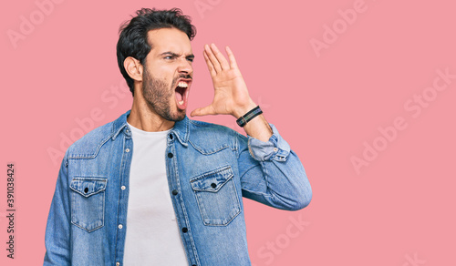 Young hispanic man wearing casual clothes shouting and screaming loud to side with hand on mouth. communication concept.