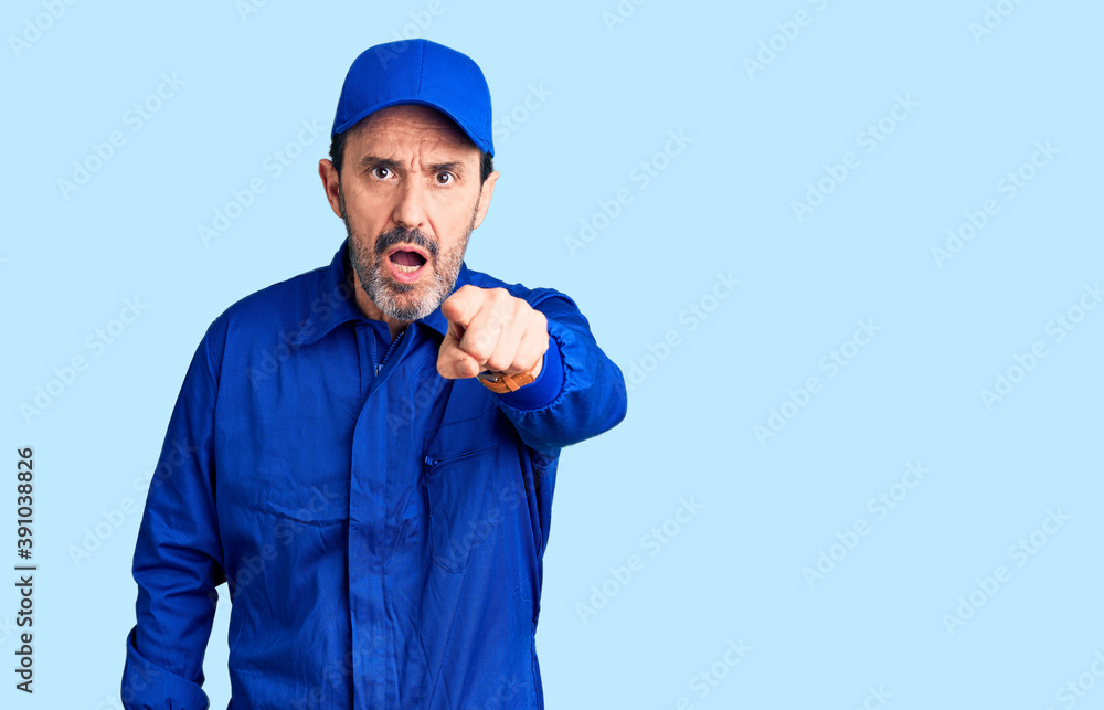 Middle age handsome man wearing mechanic uniform pointing displeased and frustrated to the camera, angry and furious with you Middle age handsome man wearing mechanic uniform pointing displeased and frustrated to the camera, angry and furious with you